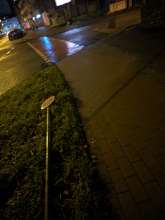 Abgeknickter Mast eines Verkehrsschildes, auf Wiese liegend