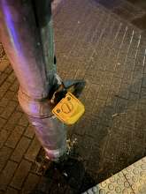 Bild zu gemeldetem Anliegen vom *2024-08-20 21:31:36 ein defekter Ampeldrücker hängt kopfüber am Kabel von der Halterung am Ampelpfosten herab.