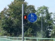 Ampel mit rotem Fußgängerpiktogramm. Daneben befindet sich die Beschilderung des gemeinsamen Geh- und Radwegs.