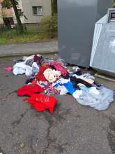 Um denn Altkleidercontainer liegen heraus gerissene Kleidung *2024-10-15 12:27:55