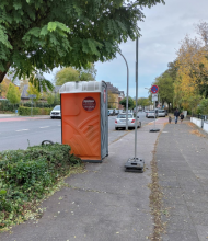 Bild zu gemeldetem Anliegen vom *2024-10-20 21:31:06 Man sieht ein Klohäuschen und zwei Verkehrsschilder mittn auf dem Radweg