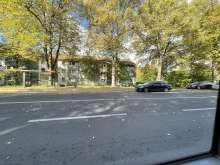 Linkeseite sind Bushaltestelle gegenüber der Straße stehen vor Einfahrt der Bushaltestelle geparkte Auto.