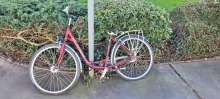 Bild zu gemeldetem Anliegen vom *2025-03-17 14:45: dunkel rotes Fahrrad ist an einem Verkehrsschild angeschlossen. Reifen sind platt und Fahrrad offensichtlich lange nicht mehr bewegt worden.