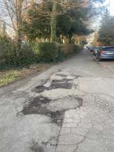 Zwischen Haus Gartenweg 14 und Friedhof ist seit Jahren eine Sammlung von Schlaglöchern, die diese von Spaziergängerinnen und Radfahrenden viel genutzte Straße sehr beeinträchtigen
