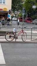 Bild zu gemeldetem Anliegen vom *2025-07-07 13:52:50 - ein rotes Fahrrad ist an einem Drängelgitter an einer Bahnhaltestelle der Linie 13 angeschlossen und steht SEHR im Weg.