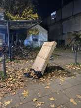 Holzelement (H100cm x B100cm x T15cm), das zwischen Gehweg und Fahrradständern abgestellt wurde