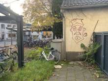 Ein Schrottfahrrad am Elektrokasten hinter den öffentlichen Fahrradständern