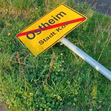 Das Foto zeigt das herausgehebelte Ortsschild in der Hans-Offermannstr. zum Waldbadviertel in Köln-Ostheim