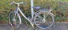 Bild zu gemeldetem Anliegen vom *2025-03-17 14: graues Fahrrad lehnt an Verkehrsschild.