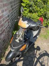 Moped mit einem offenen Motor. Auf dem Lenker klebt ein abgerissenes orangenes Schild