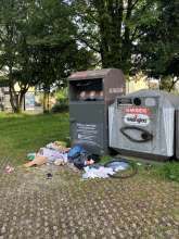 Müll auf dem Boden vor Kleidercontainer am Großparkplatz Thuleweg