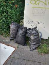 Drei Säcke mit Styropor hinter Kleidercontainer am Parkplatz des SOK-Marktes