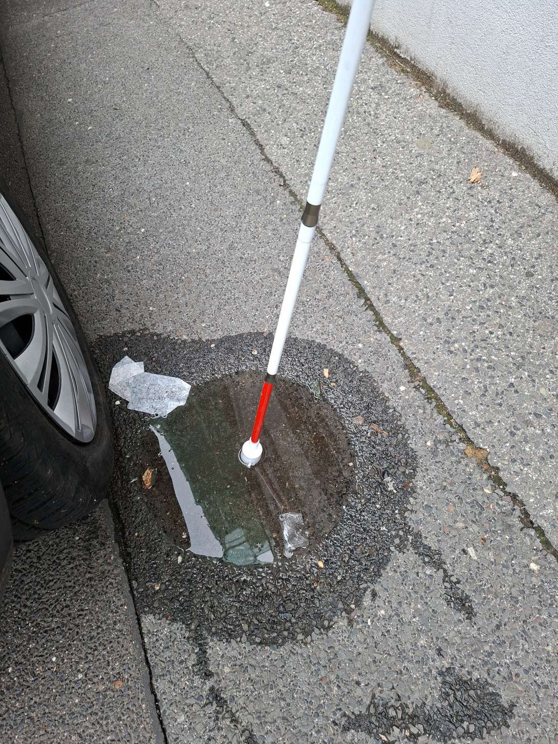 Bild zeigt das Schlagloch mit 3cm Tiefe. Als Maßstab dient ein Blindenstock. 
